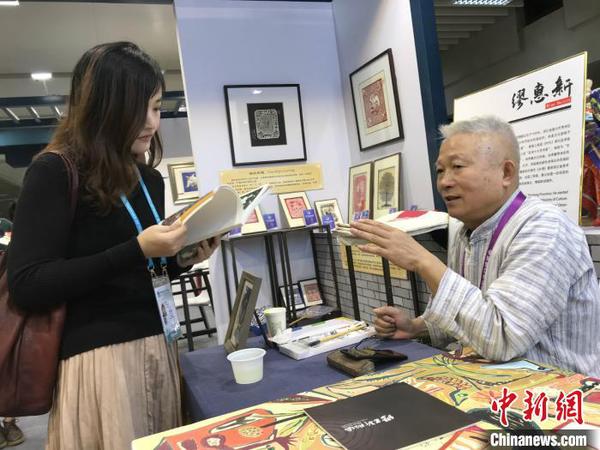 秀洲農民畫畫家繆惠新和參觀者交流。供圖
