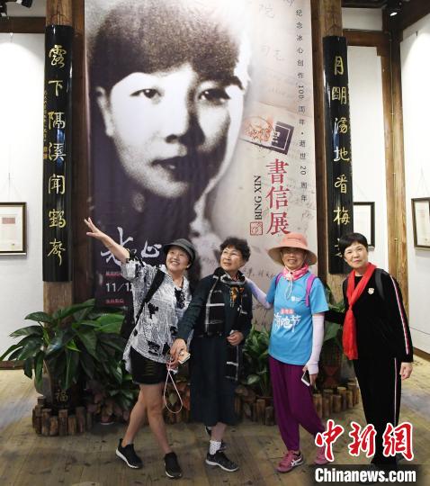 觀眾在展出的冰心青年時期黑白老照片前合影?！∮浾邉⒖筛?攝