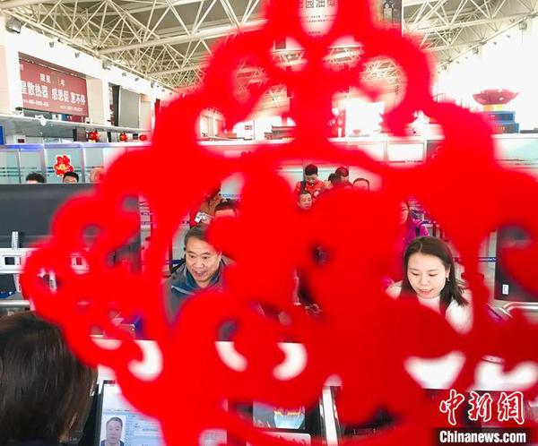 “春節裝飾”扮靚出入境邊防檢查執勤現場。圖為民眾排隊通過驗證臺?！“瑧c龍 攝