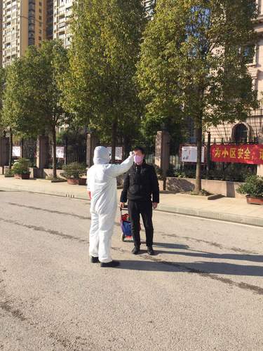 圖為楊偉偉的弟弟在下沉社區幫助進入人員測體溫。