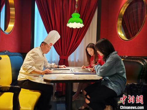 5月24日，記者在濟南一魯菜館見到網絡主播李頔時，她正在餐館中向廚師了解當天所要進行“吃播”的魯菜菜式、文化及用料選材方面的講究?！『聦W娟 攝