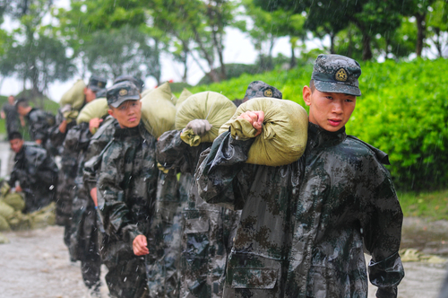 圖為在安徽合肥巢湖任務區官兵在暴雨中扛運沙袋，加固堤壩。（王文洲 攝）