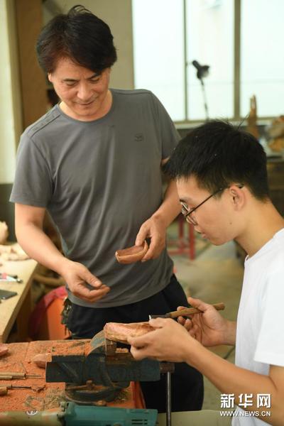 5月24日，徐惠東（左）在位于下涯村的工作室指導徒弟洪明進行茶則制作。新華社記者 翁忻旸 攝