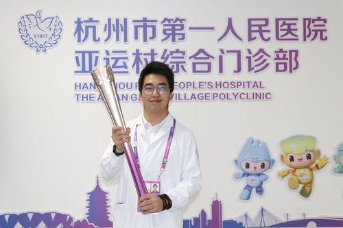 吳玨燦和杭州亞運會火炬“薪火”合影（人民政協報社，受訪者供圖）
