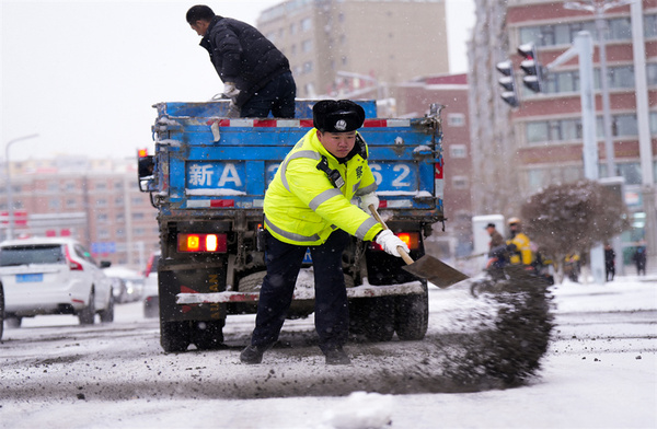 烏魯木齊市交警支隊(duì)的輔警正在向路面拋灑爐渣，防止車輛打滑。冶占飛 攝
