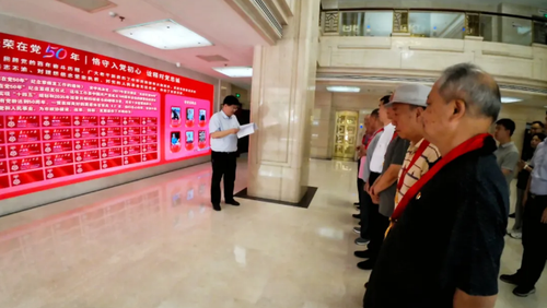 老黨員們來到“光榮在黨50年”榮譽墻前，莊重地貼上寫有自己名字的榮譽牌。